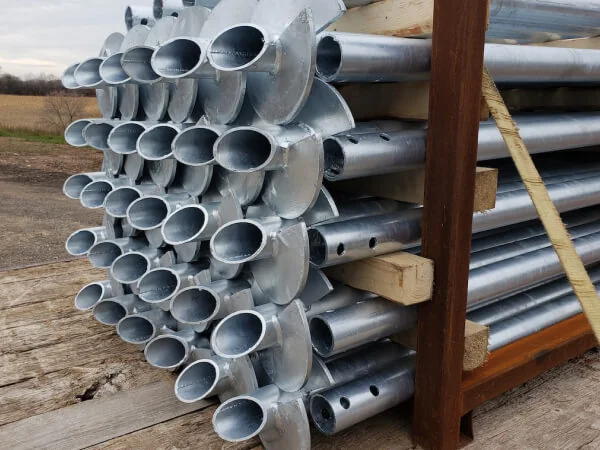Stacked galvanized steel helical piles ready for installation